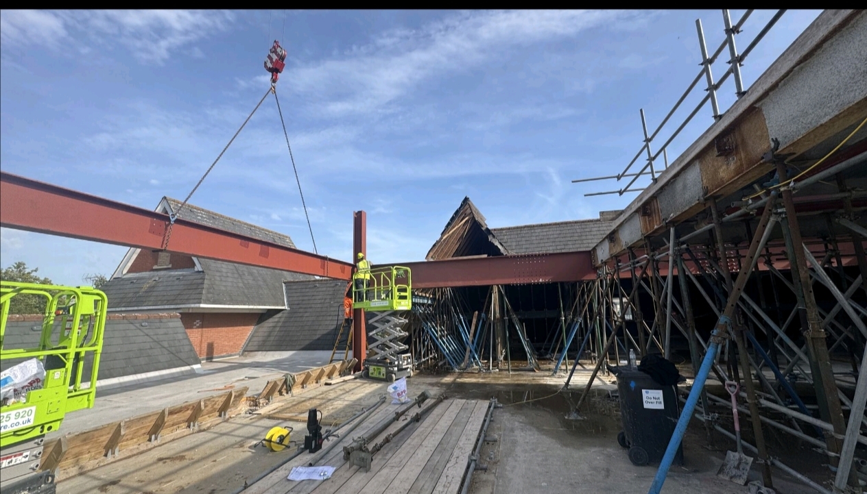 Crane-assisted steel beam installation on construction site